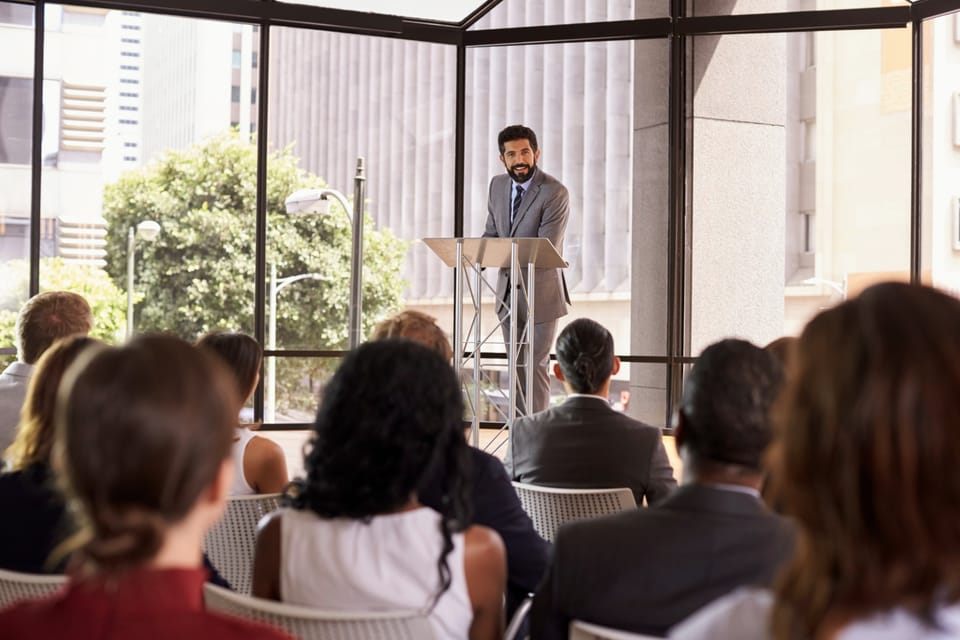 Palestrante em um púlpito apresentando para a plateia em um evento corporativo